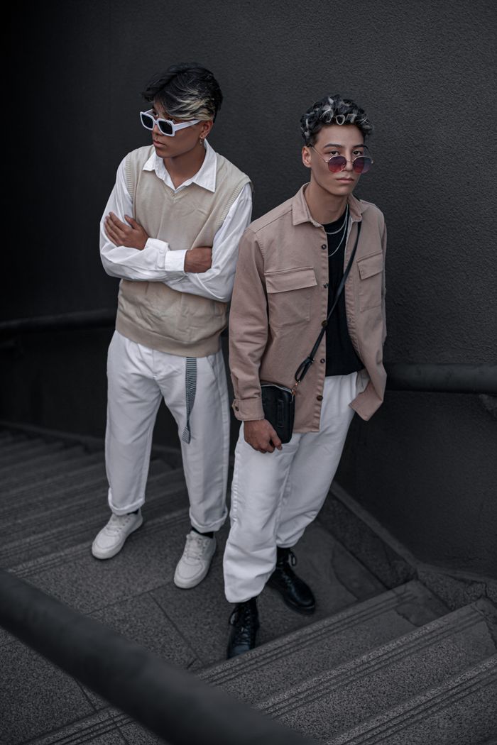 contact-img Stylish young men in beige and white outfits posing on stairs, embodying modern fashion trends.